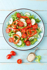 Healthy vegetarian vegetable salad of fresh lettuce, cucumber, sweet pepper and tomatoes. Vegan plant-based food. Flat Lay. Top view