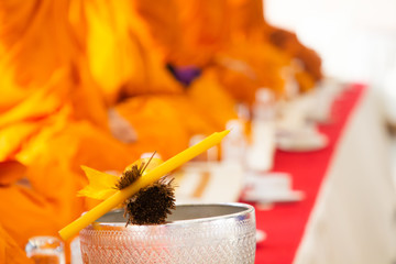 buddhist monk , yellow candle and holy water in silver thai pattern bowl .