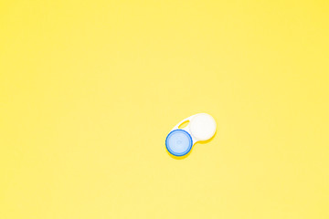 Container for contact lenses on yellow background, top view