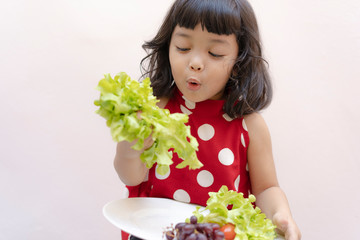 Asian kid girl with  fresh green vegetables.