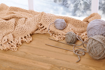 Woolen yarn and fabric on the window sill. Beautiful view outside the window - winter scenery and snow.