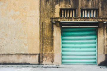 abandoned factory building, old yellow storage warehouse building with closed green metal roller shutter door in vintage effect, copy space, Taipei, Taiwan