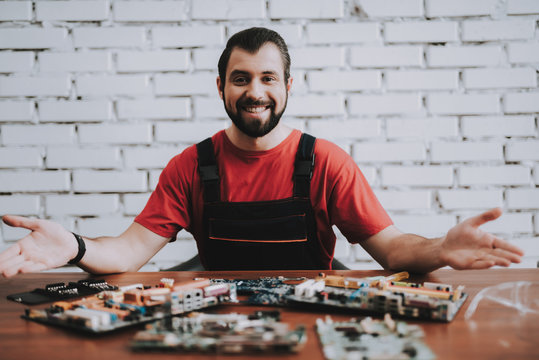 Man in Uniform with Broken Motherboards in Shop.