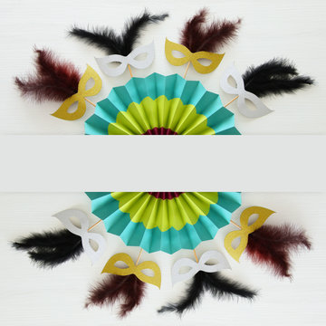 carnival party celebration concept with masks and colorful fan over white wooden background. Top view - Image.