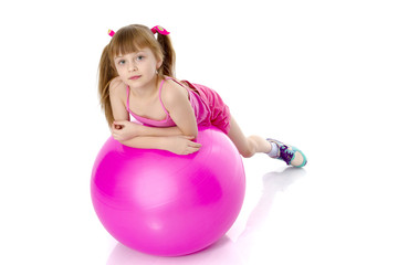 little girl doing exercises on a big ball for fitness.