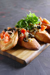 Crispy toasts with tomato, olives, arugula and cheese