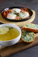 Clear chicken broth with egg served with toasts