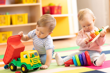 Kids playing with educational toys. Children sit on a rug in a play room at home or kindergarten....