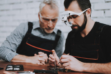 Two Men Repairing Hardware Equipment in Workshop.
