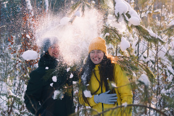 young beautiful man and woman standing close to each other under fallen snow , spend winter...