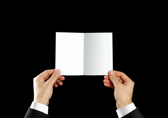 Hand holding blank brochure booklet in the hand. Isolated on black background. Man show offset...