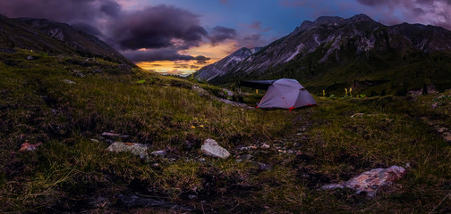 Panorama tent in the mountains on a background of purple clouds at sunset