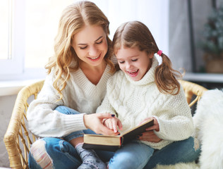 happy family mother reads book to child to daughter by window .