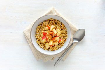 Bowl of oatmeal with apple against white table