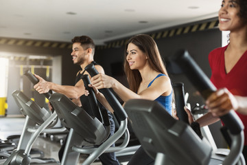 Group of athletes using cross-trainers in sport club