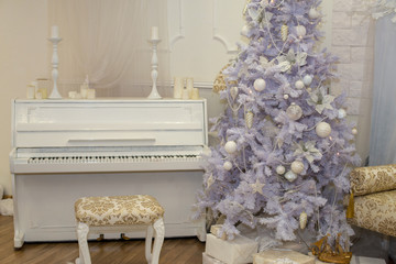 White Christmas tree decorated with silver and pink ornaments at the piano background.Winter scene. New Year decoration.Xmas interior design includes decorated Christmas tree.Selective focus.Classical