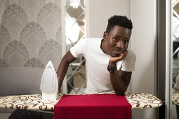 African man ironing clothe at home