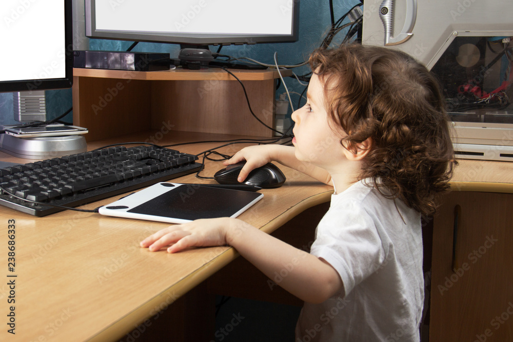 Fototapete Little 2 3 year old baby girl in white clothers draws at the home computer in graphics drawing tablet. two monitors. The child is holding a mouse. Mock up vith copy space for text