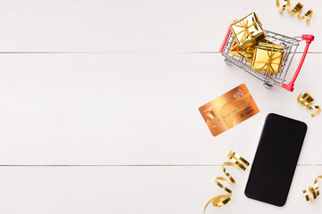 Smartphone, credit card and trolley with gifts