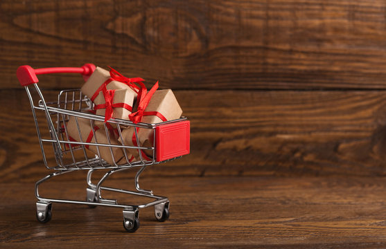 Craft christmas gifts in shopping cart over wooden background