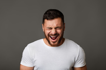Obraz premium Young man in white t-shirt grimacing and crying
