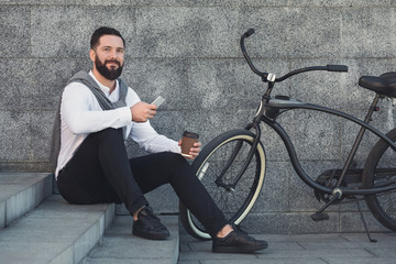 Obraz na płótnie Canvas Businessman on coffee break, sitting on stairs and using smartphone