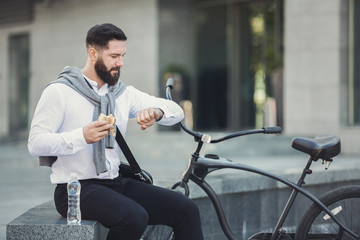 Businessman checking time on his watch eating lunch