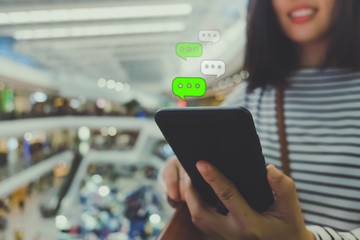 Woman hand using smartphone with chat icon in cafe shop background.