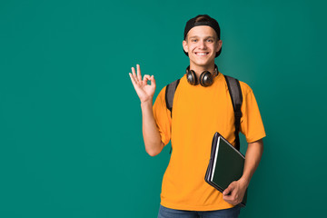 Student guy showing ok sign over turquoise background - obrazy, fototapety, plakaty