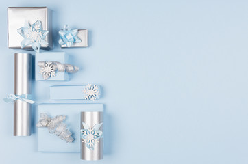 Airy soft cold winter season celebration background in pastel blue and silver color with different gift boxes as decorative border, top view.