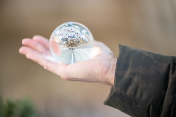 Man’s hand holding large crystal ball with modern station interior reflected in it