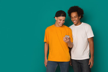 Two teenage guys using smatphone on blue background