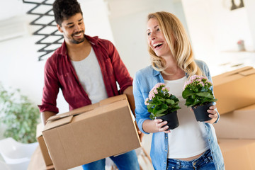 Young couple unpacking cardboard boxes at new home moving in concept