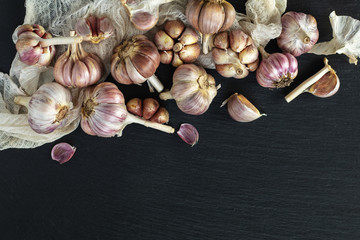 Fresh garlic on a black stone surface, top view, copy space