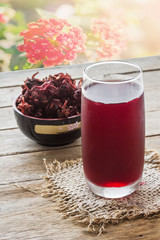 Roselle juice on table, flower background, raw roselle in cup,