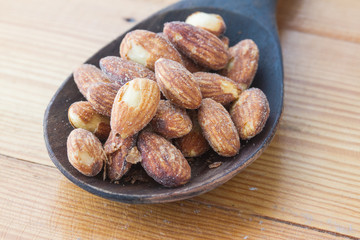 almonds on wooden ladle, wooden table,