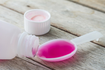 liquid medicine in plastic spoon on wooden table.