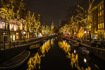 Fototapeta na wymiar beleuchtete Gracht mit Booten in Amsterdam bei Nacht