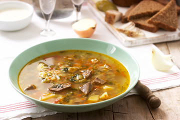 Rassolnik, traditional Russian soup, served with various snacks and vodka. Rustic style.