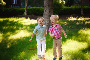 Fototapeta premium Dwóch braci chłopców gra i skoki na świeżym powietrzu w parku.
