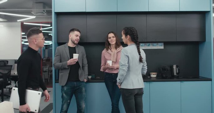 Three colleagues office workers having a conversation during a coffee break in a modern office. 4K UHD 60 FPS SLOW MOTION