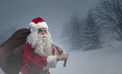 Santa carrying a sack with gifts under the snow