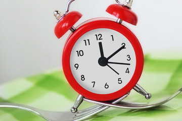 Forks holding alarm clock on plate - Time to eat concept