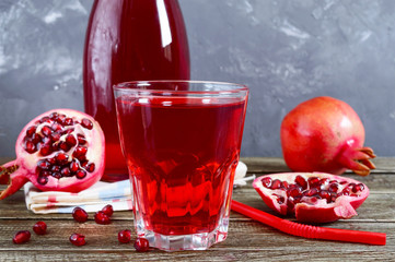 Ripe pomegranate fruit, bottle and glass of fresh pomegranate juice on wooden table. Healthy eating concept.