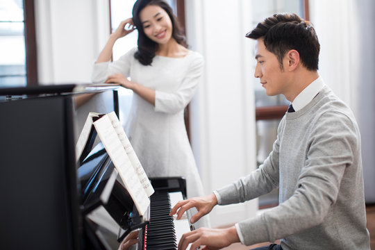 Noble young couple playing the piano together
