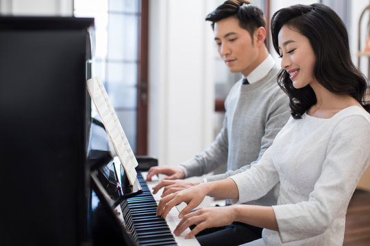 Noble young couple playing the piano together
