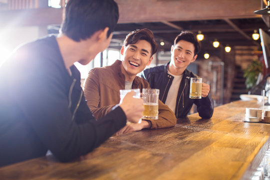 Happy young men drinking beer in bar