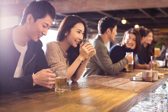 Happy friends drinking beer and talking in bar - Powered by Adobe