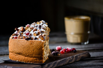 Coffe and homemade cake with nuts and fruits on dark wood background, recipe. Right view.
