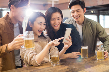 Happy friends using smartphone in bar